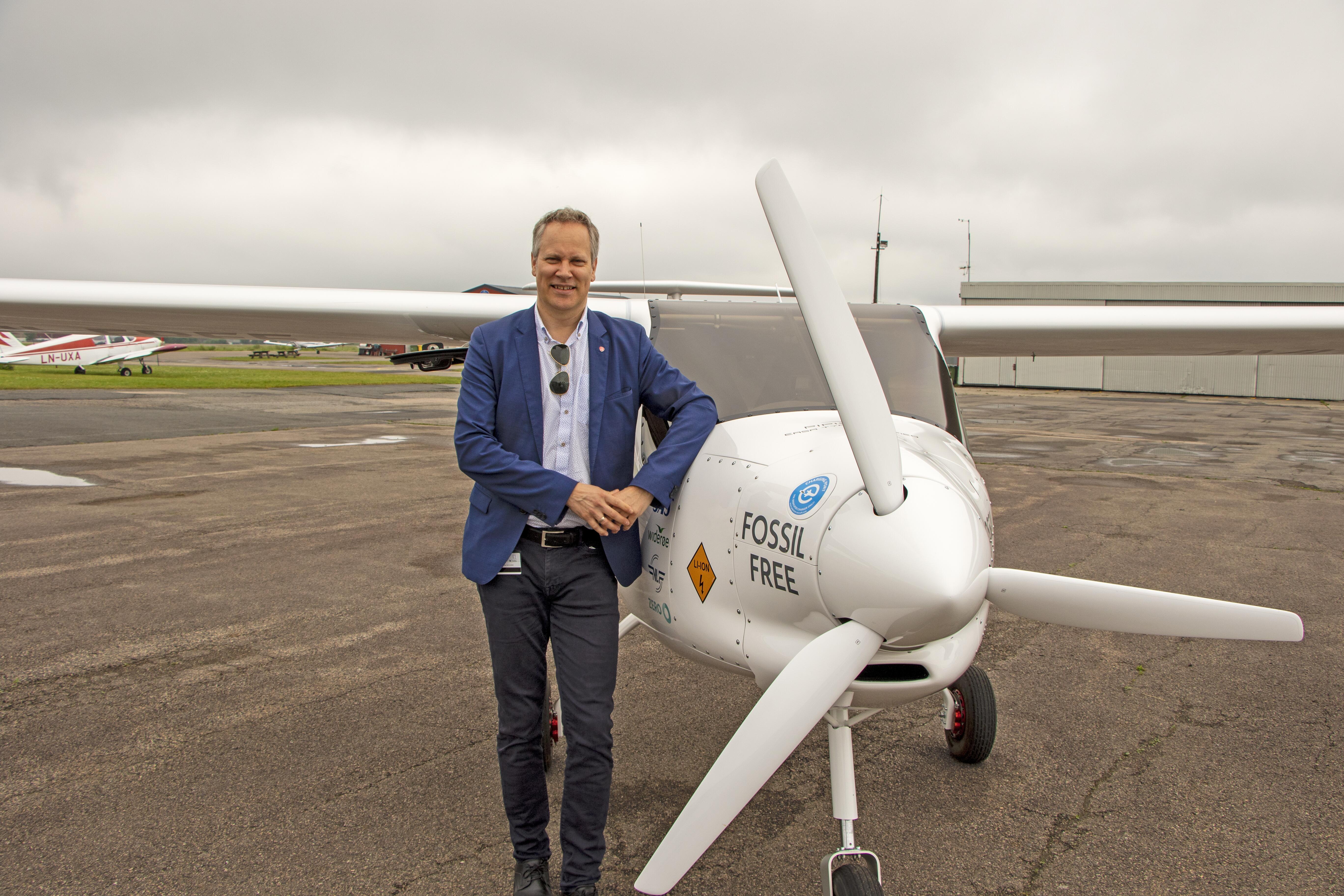 Samferdselsminister Jon-Ivar Nygård står ved et propellfly ute. 